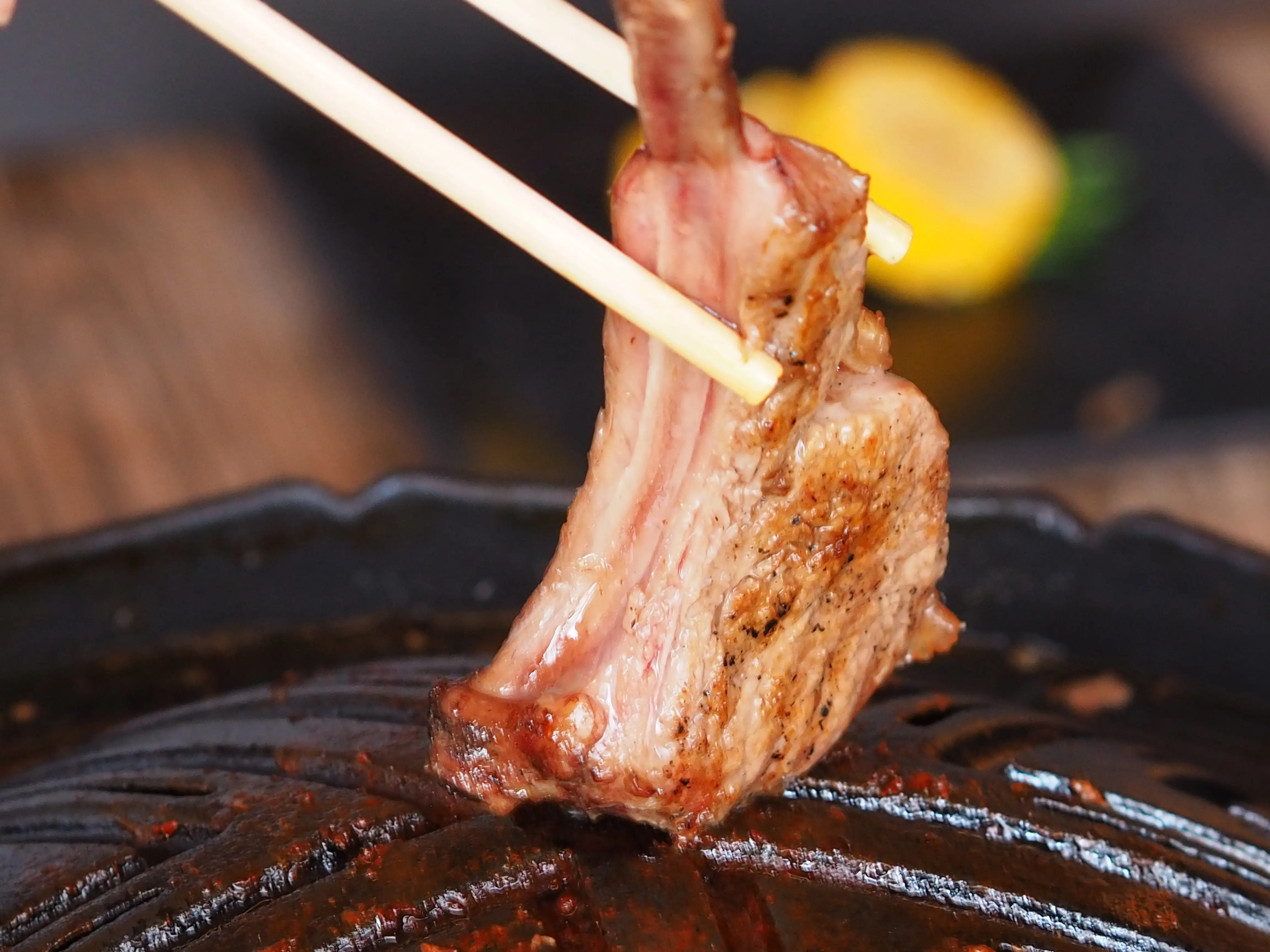 焼いたラム肉をお箸で持ち上げている写真